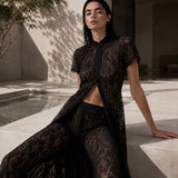 Black organic cotton lace cape top and wide-leg trousers set — sheer floral lace. PHAGE Paris